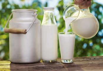 Pouring milk in the glass on the background of nature.