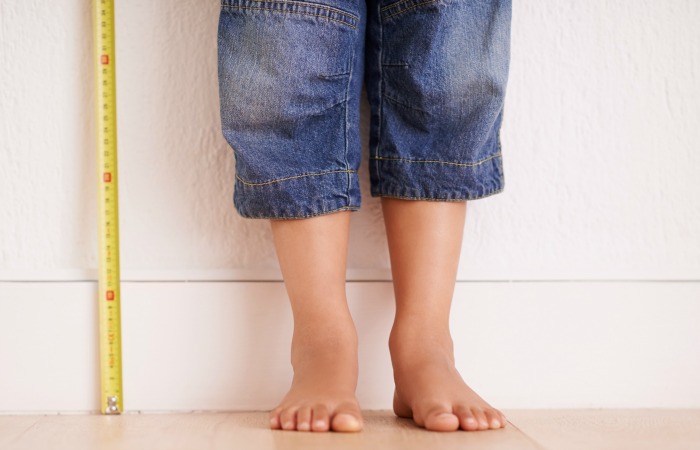 Cropped shot of a young boy standing next to a tape measure